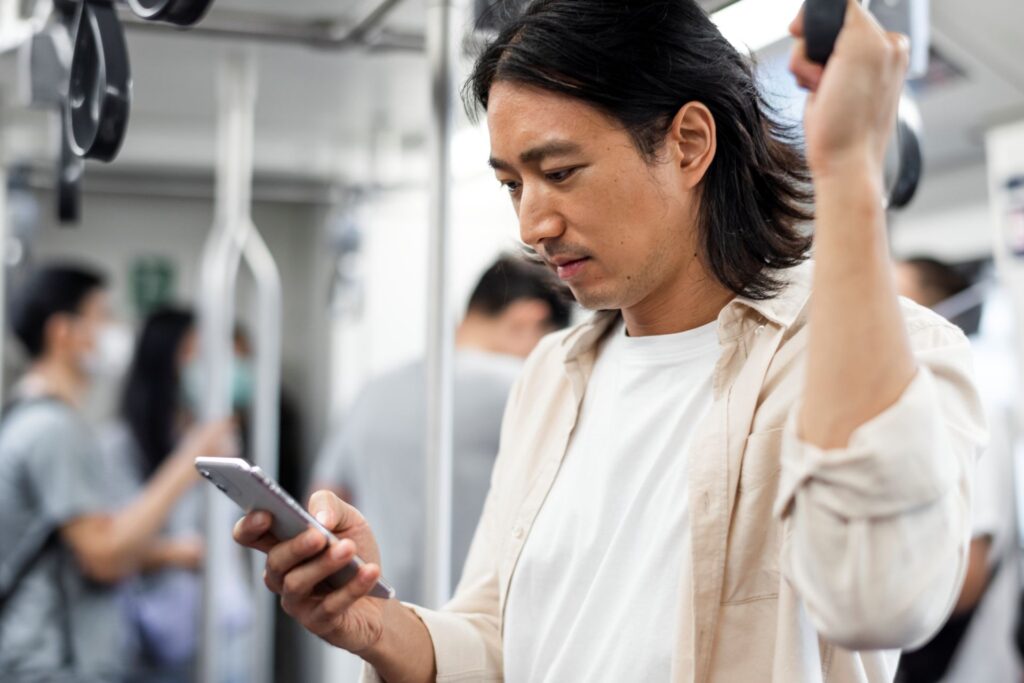 Japanese man scrolling his phone while train